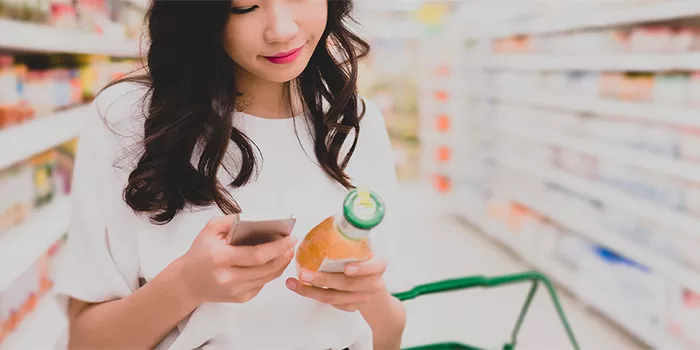 A person checking the ingredients on a bottle of juice in a supermarket.